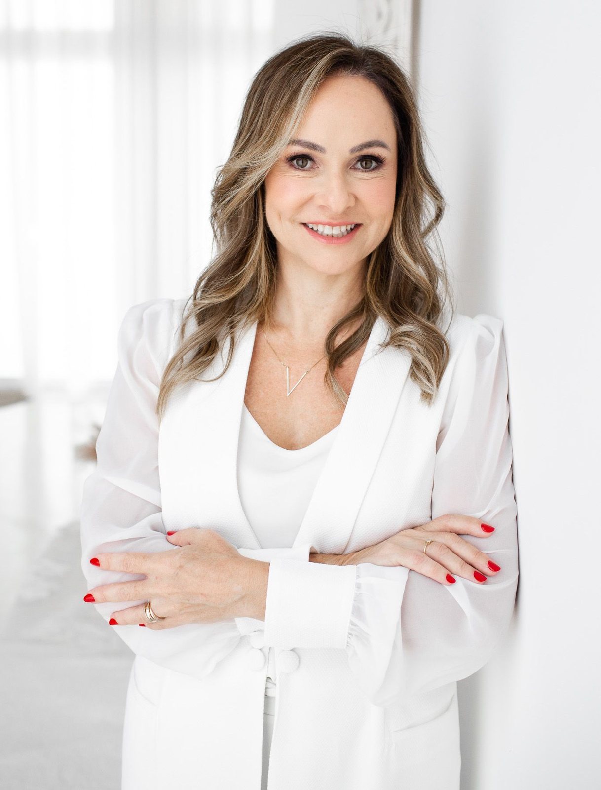 Dra. Alessandra Nalin, de blazer branco, braços cruzados, sorrindo